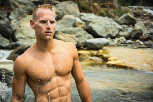 Handsome young muscle man standing in water pond