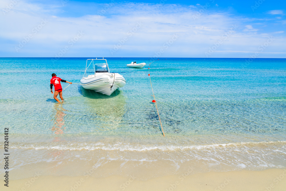 Lifeguard pulling boat to shore on Villasimius beach, Sardinia