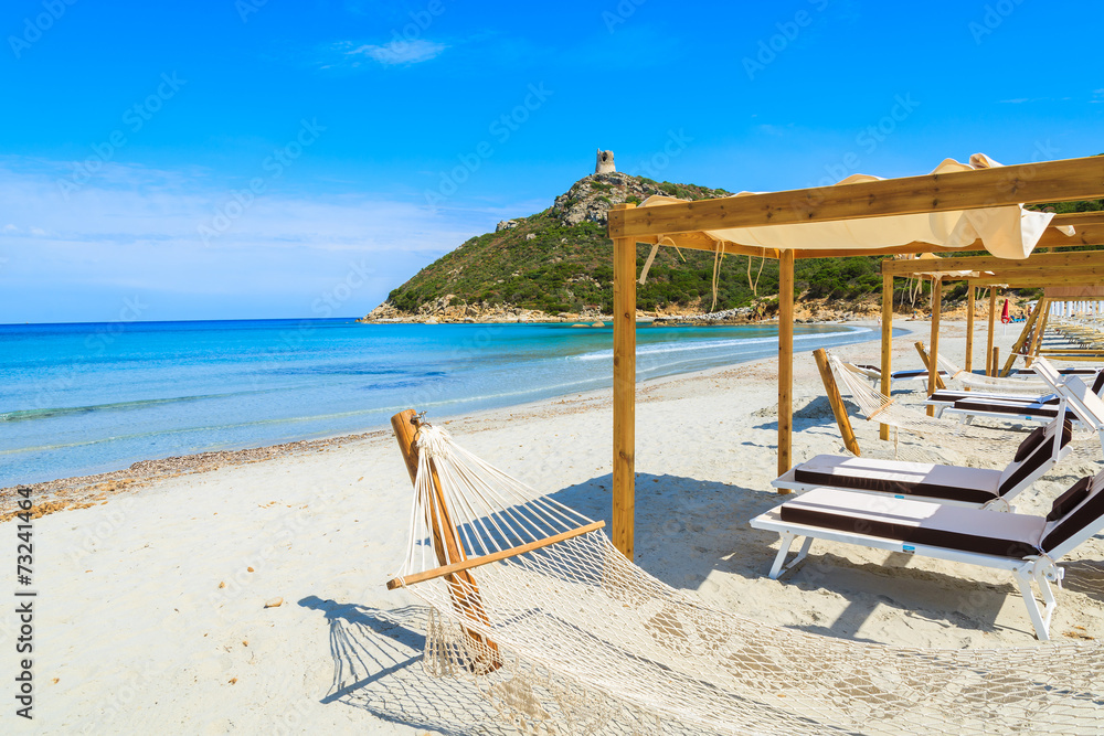 Hammocks on white sand beach in Porto Giunco bay, Sardinia