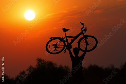 Tourist with a bike on the sunset background.