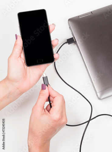 Woman connecting Smartphone to a notebook  for powering