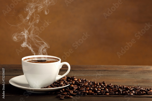 Fotografie, Obraz Black coffee in white cup with smoke and coffee beans on brown b
