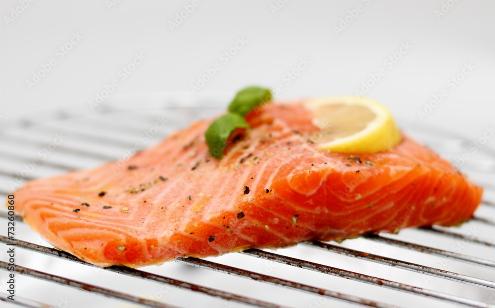 Marinated salmon fillet with lemon on grill, soft focus