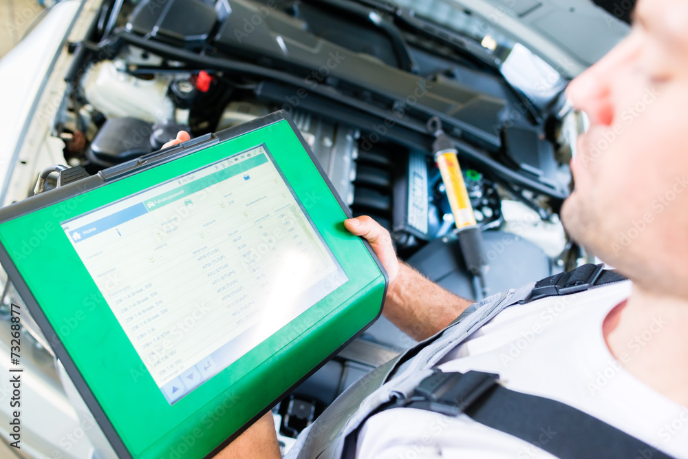 Automechaniker mit Diagnosegerät in Autowerkstatt Automechaniker mit Diagnosegerät in Autowerkstatt