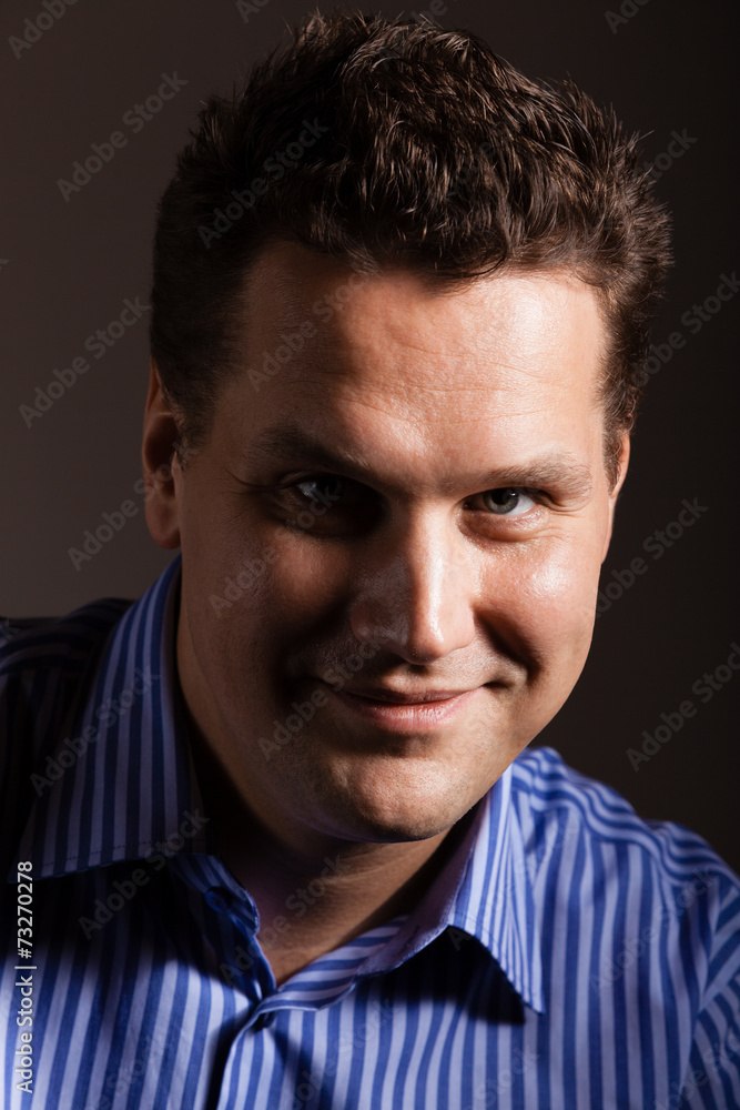 Portrait of young man in blue shirt on dark gray