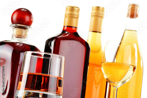 Bottles and glasses of assorted alcoholic beverages over white
