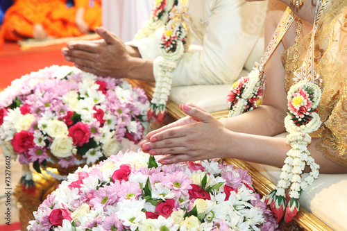 Hands pouring blessing water into bride's hands inThai ceremony.