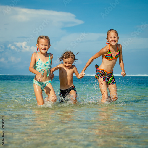 three happy kids playing on beach at the day time