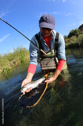 Fly fisherman holding recently caught fish