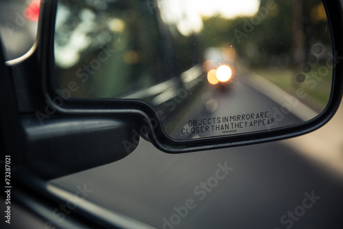 Side rear view mirror of a car on a road