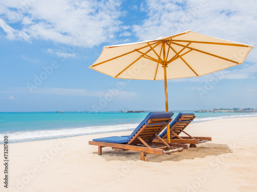 Relaxing couch chairs with parasol on white sandy Beach