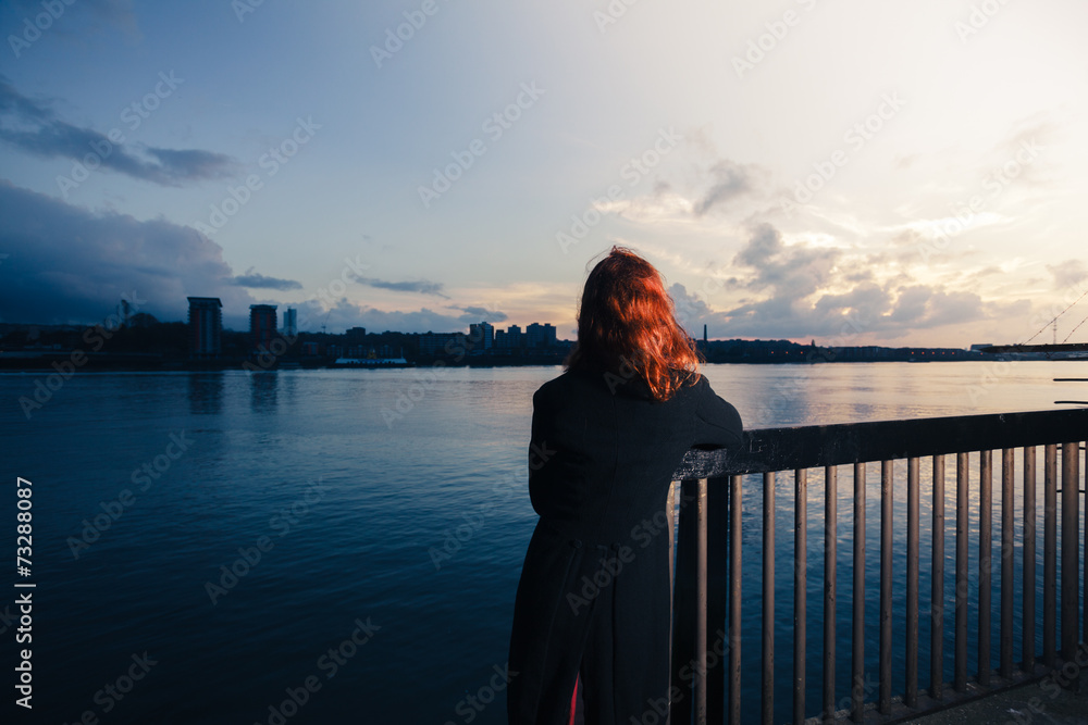 Woman admiring sunset over river in city