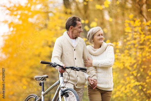 Senior couple with bicycle in autumn park