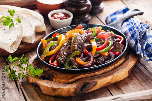 Photo Beef Fajitas with colorful bell peppers in pan and tortilla brea