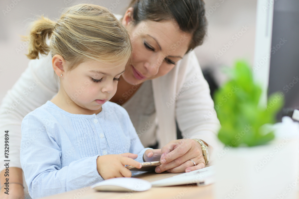 Mother and daughter using smartphone, home office Mother and daughter using smartphone, home office