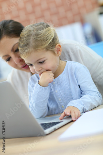 Mother and little girl using laptop computer
