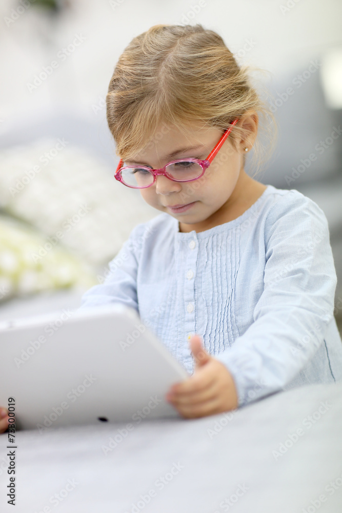 Cute little girl playing with digital tablet