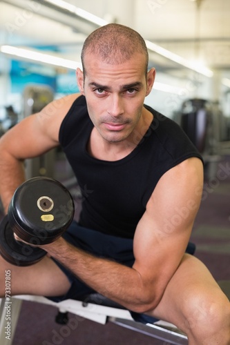 Portrait of man exercising with dumbbell in gym