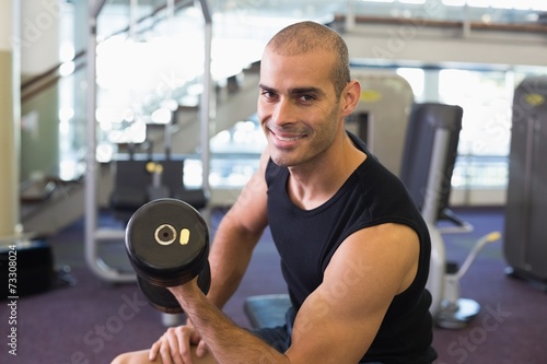 Portrait of man exercising with dumbbell in gym