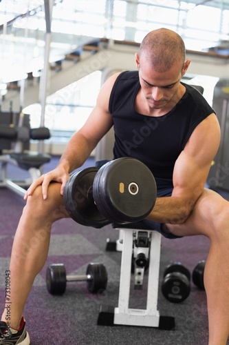 Young man exercising with dumbbell in gym