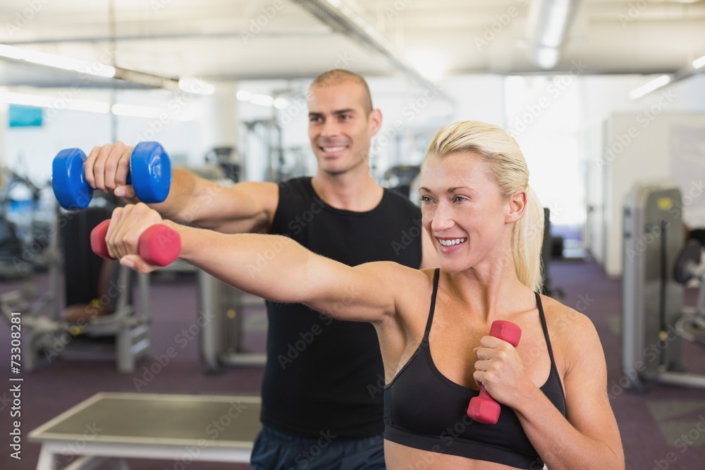 Couple exercising with dumbbells in gym Couple exercising with dumbbells in gym
