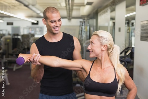 Male trainer assisting woman with dumbbell in gym © WavebreakmediaMicro