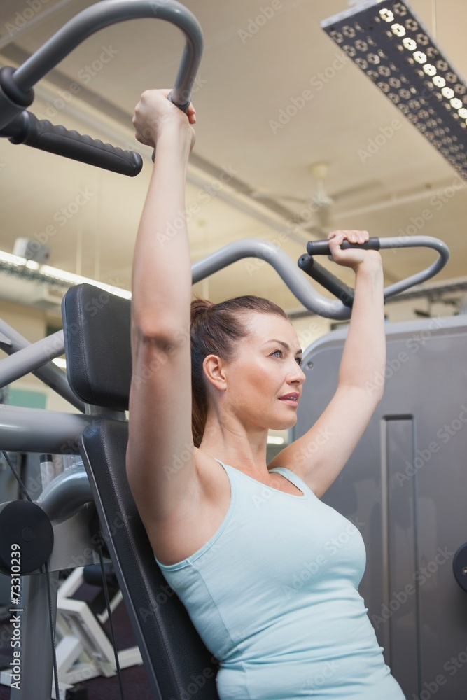 Fit brunette using weights machine for arms Fit brunette using weights machine for arms