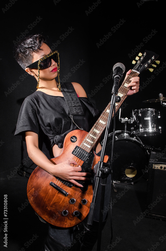 Fototapeta premium Young woman playing guitar during the concert