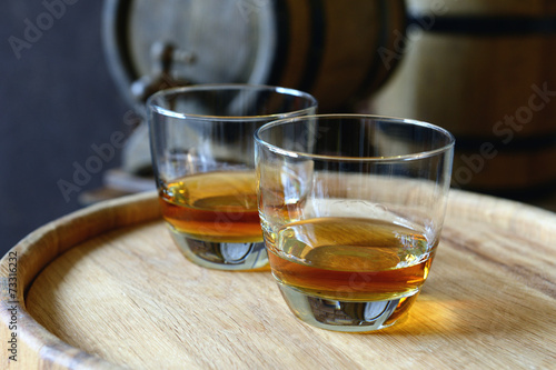 Glasses of brandy in cellar with old barrels