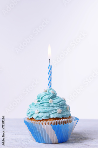 Delicious birthday cupcake on table on white background