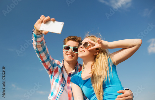 smiling couple with smartphone making selfie