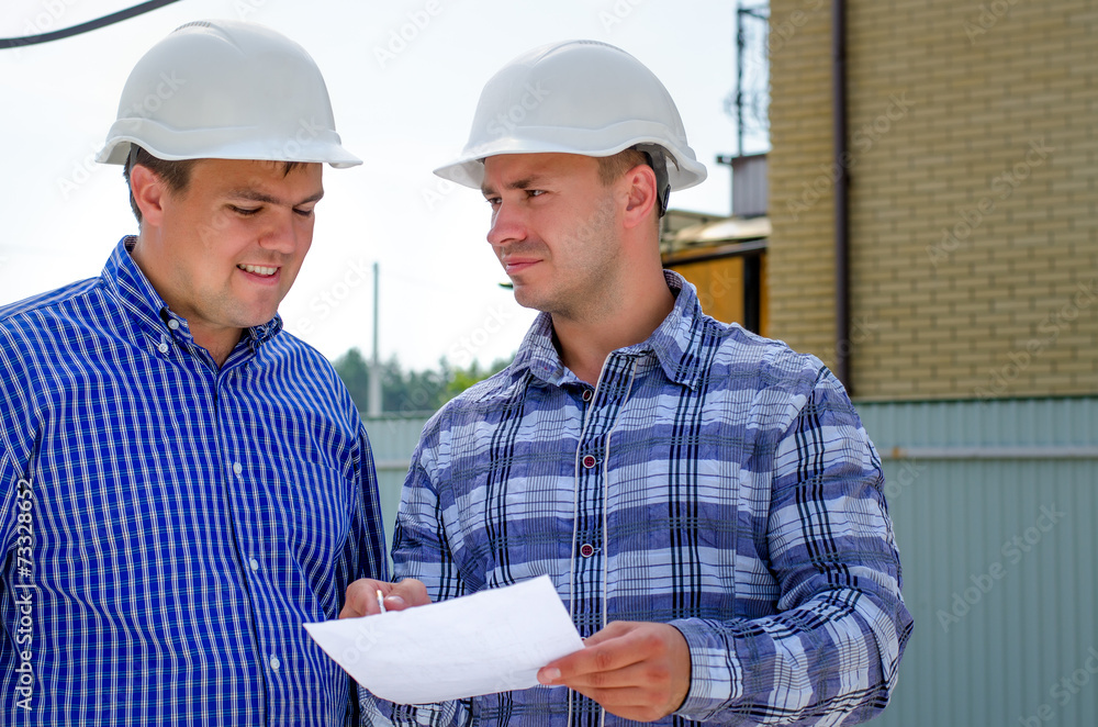 Two builders or engineers discussing paperwork Two builders or engineers discussing paperwork