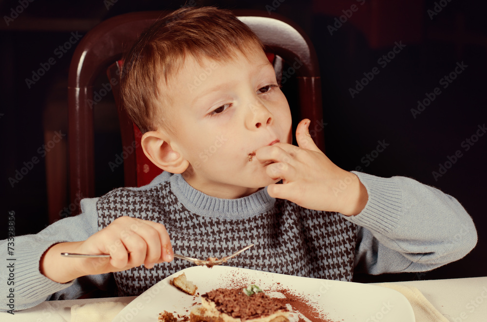 Little boy licking his fingers in appreciation