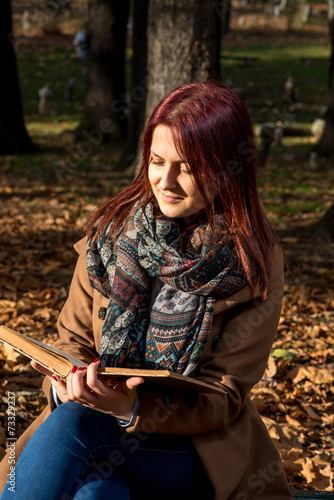Redhead girl sitting on bench in park