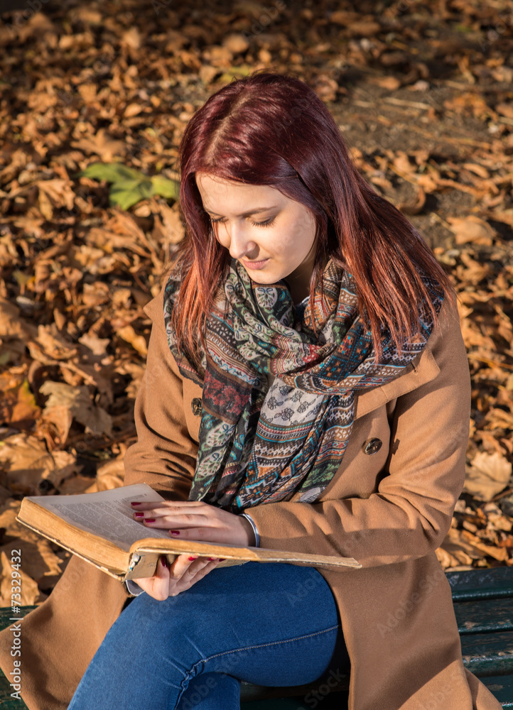 Redhead girl sitting on bench in park Redhead girl sitting on bench in park