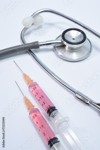 Medical syringes and stethoscope on white background.