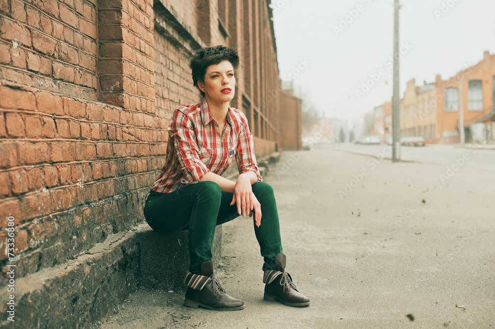 Woman wearing checkered shirt and jeans. Short hair