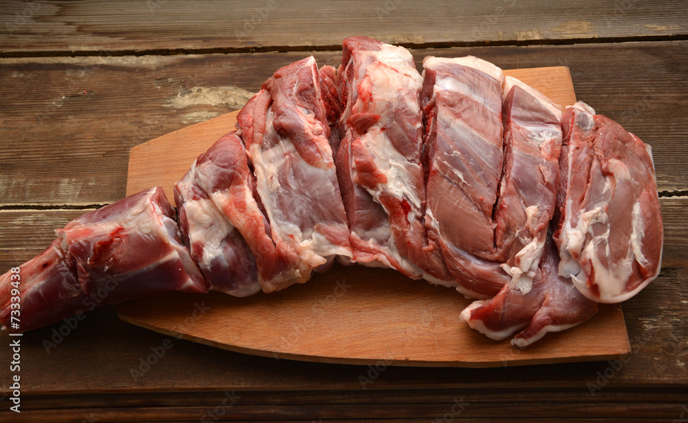 Fototapeta premium Raw lamb leg on a wooden table