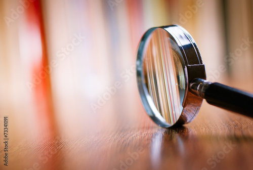 Valokuvatapetti Close up Magnifying Glass Leaning on Wooden Table