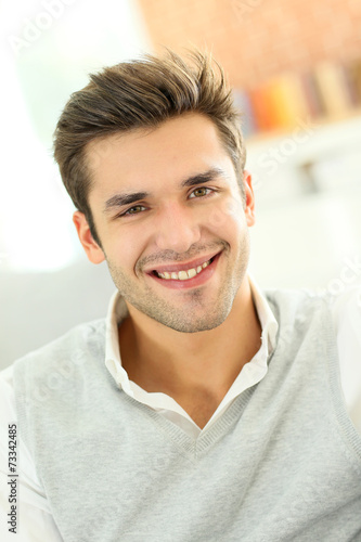 Portrait of smiling casual guy sitting in sofa