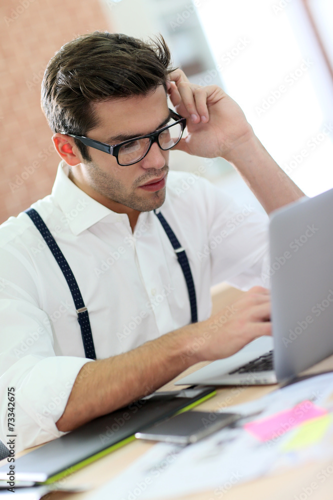 Trendy young man working in office with laptop Trendy young man working in office with laptop