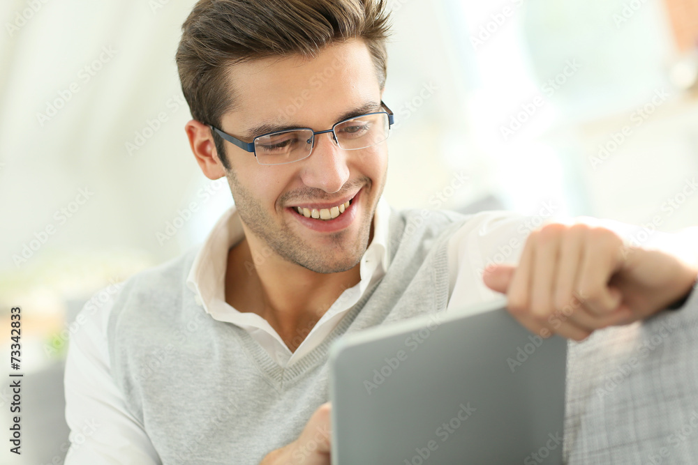 Young man websurfing with tablet, sitting in sofa Young man websurfing with tablet, sitting in sofa