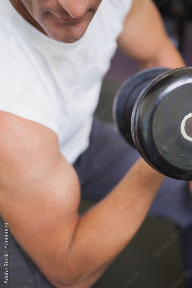 Fit man lifting dumbbells sitting on the bench Fit man lifting dumbbells sitting on the bench