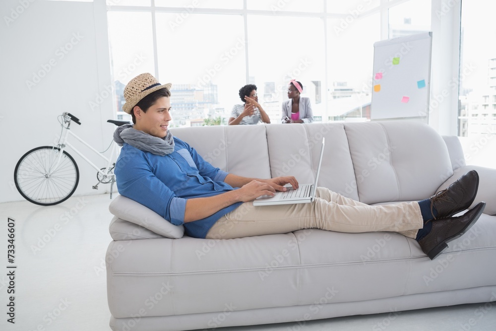Young creative man using laptop on couch Young creative man using laptop on couch
