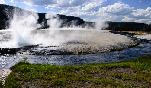 Erupting geyser on a riverbank in Yellowstone national park
