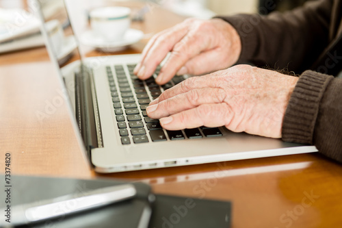 Senior working with Laptop, focus on hands