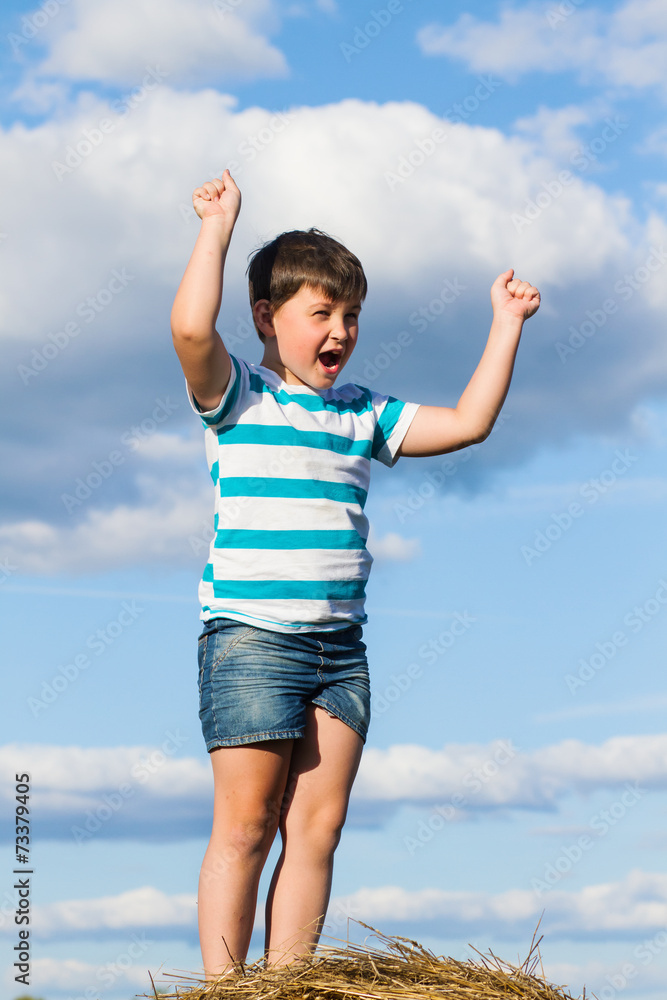 Little boy on a haystack with raised hands Little boy on a haystack with raised hands