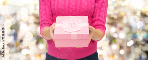 close up of woman in pink sweater holding gift box
