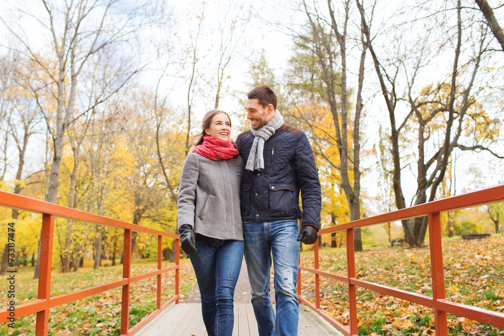 smiling couple hugging on bridge in autumn park