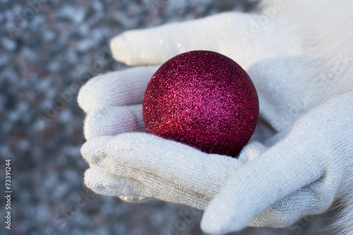 Voman giving christmas tree ball wearing red gloves photo